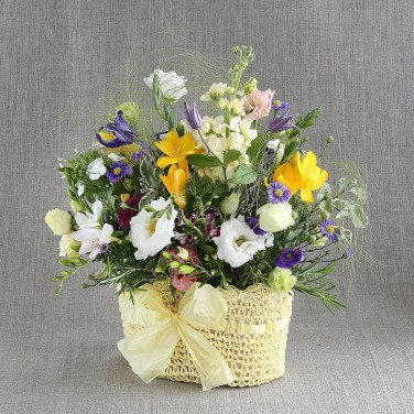 Оригинальная композиция в вязанном кашпо с фрезиями, барбареллой и эустомой