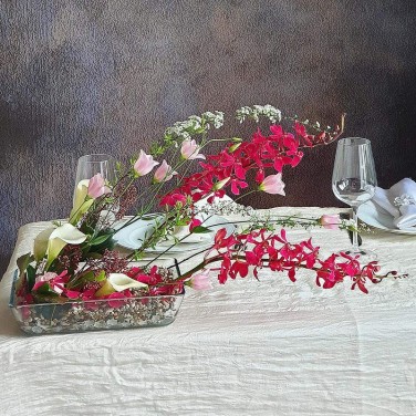 Оригинальная композиция на стол из калл, орхидей и прунуса