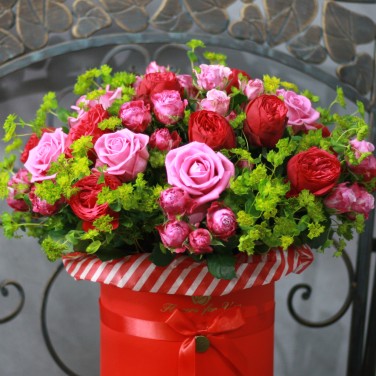 Композиция в красной шляпной коробке из пионовидных роз и зелени