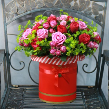 Композиция в красной шляпной коробке из пионовидных роз и зелени