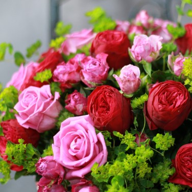 Композиция в красной шляпной коробке из пионовидных роз и зелени