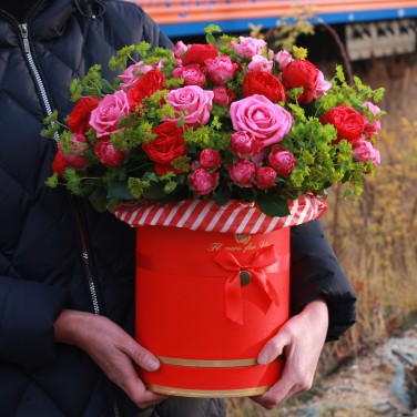 Композиция в красной шляпной коробке из пионовидных роз и зелени