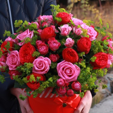 Композиция в красной шляпной коробке из пионовидных роз и зелени